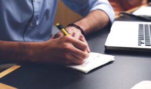 taking notes next to laptop