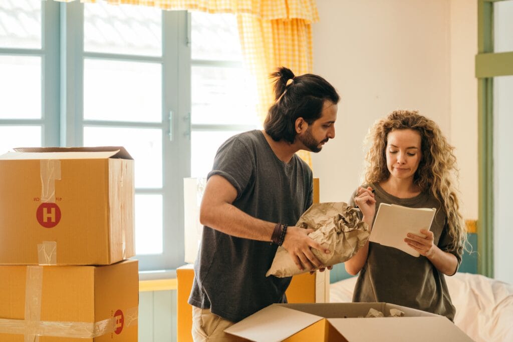 Couple packing moving boxes and looking at a checklist.